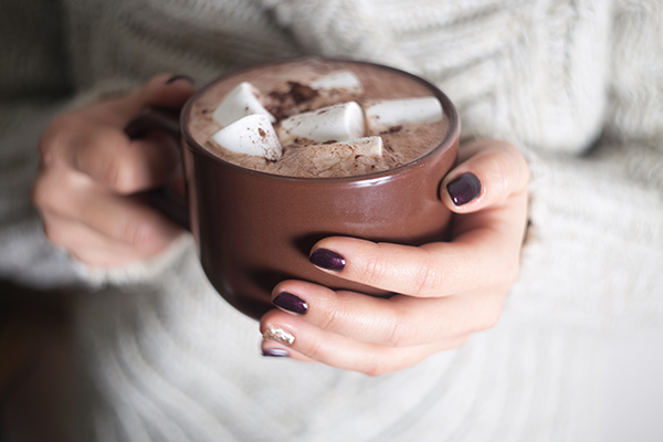 A mug with hot cocoa and marshmallow in the hands of the girl.