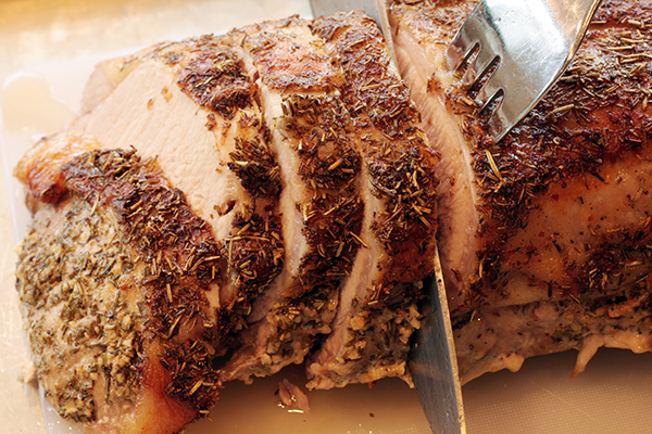 'Carving a pork roast rubbed with a mixture of garlic, salt, chrushed rosemary and olive oil before roasting