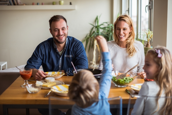 Happy family enjoying lunch while kids playing.