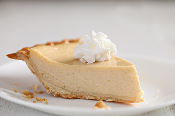 An extreme close up of a Southern favorite, a slice of chess buttermilk pie with a generous portion of whipped cream.