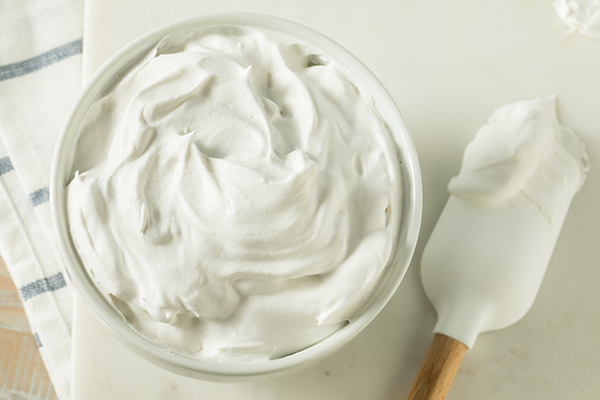 A spatula and a bowl of marshmallow cream frosting.