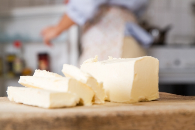 Slices of margarine on a kitchen counter with a woman in the background getting an item out of the fridge.