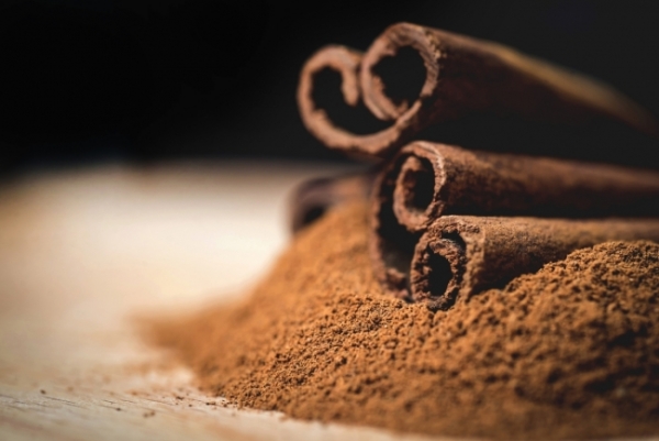 Cinnamon sticks with cinnamon powder on wooden background