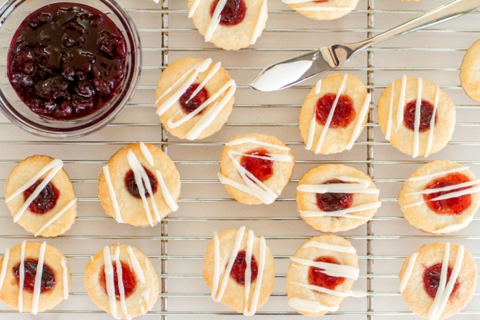 Strawberry Thumbprint Cookies a photo of thumbprint cookies, stuffed with both cherry and strawberry preserves, then drizzled with a vanilla and cream cheese icing.