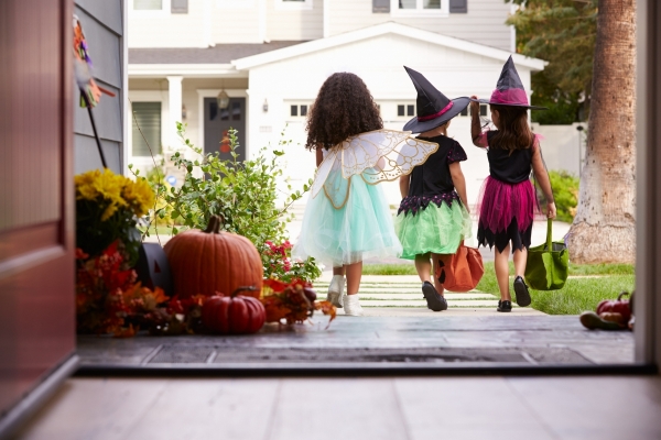 A group of three trick-or-treaters walking down the driveway