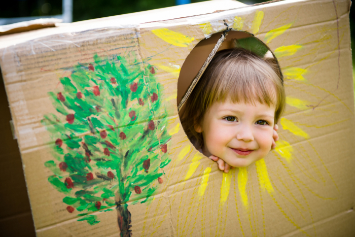 Child in a decorated cardboard box fort