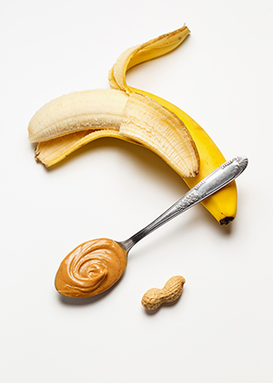 A halfway peeled banana with a spoonful of peanut butter