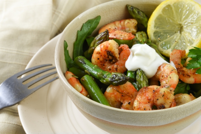 Garlic Herbed Shrimp with Asparagus salad from prawn shrimp, green asparagus, arugula and lemon slice in a bowl on a plate, festive appetizer or buffet snack