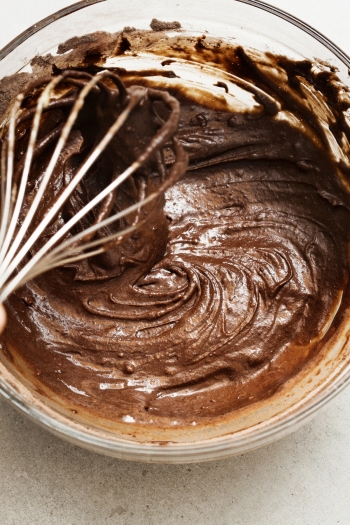 Someone mixing chocolate cake batter with a mixer and a mixing bowl