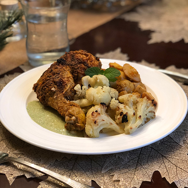 Roast chicken with vegetables and sauce on a festive plate setting.