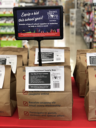 A picture of a table with Brown Bags of Hope and a sign that says "Equip a kid this school year!"